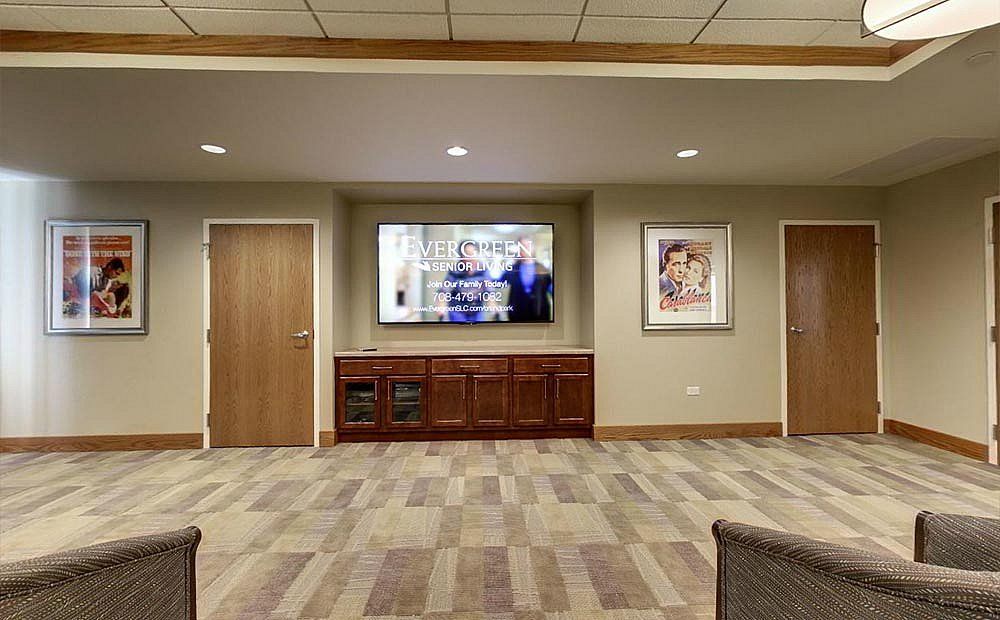 A waiting room with a television, two doors, and artwork on the walls.