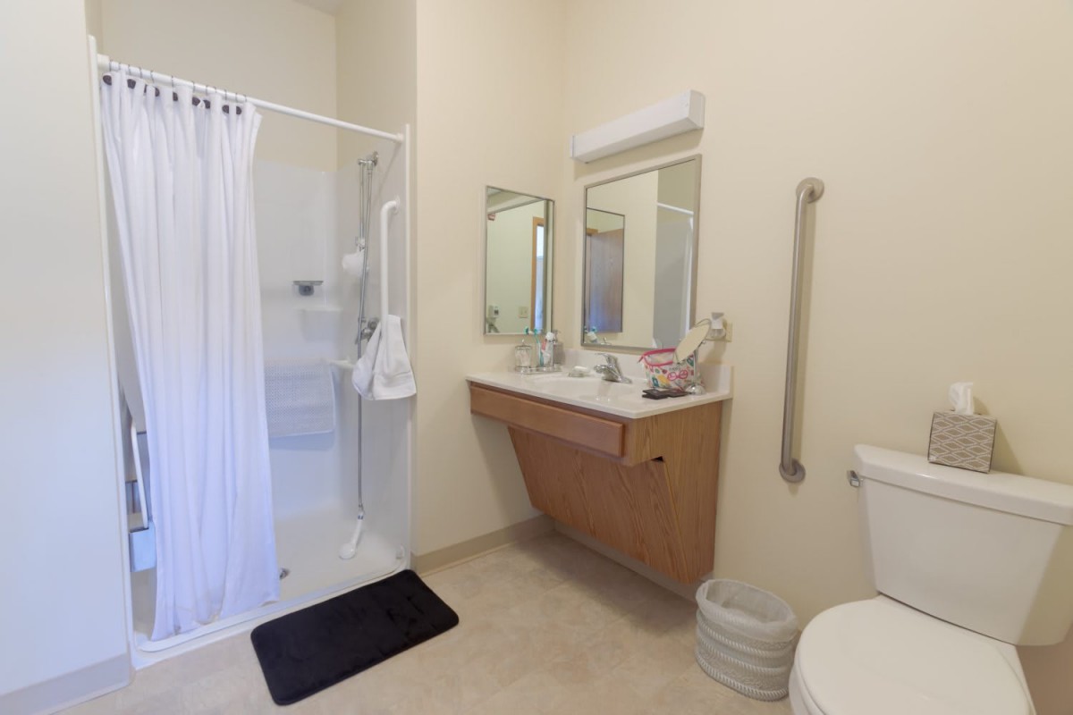 An accessible bathroom with a shower, sink, and toilet.