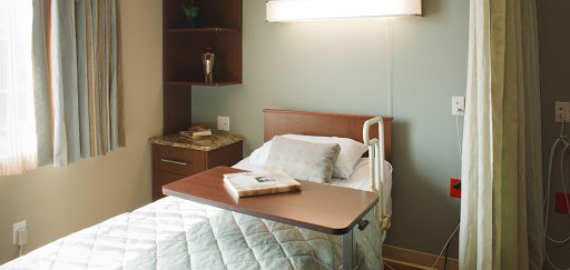 A serene hospital patient room featuring a comfortable bed and essential medical furnishings.