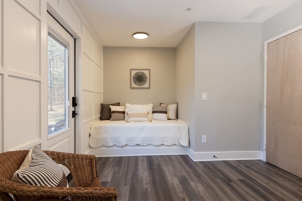 A minimalist bedroom with a cozy daybed and wooden flooring.