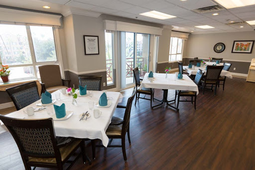 An elegantly arranged dining area with tables set for guests, complemented by natural lighting and tasteful decor.