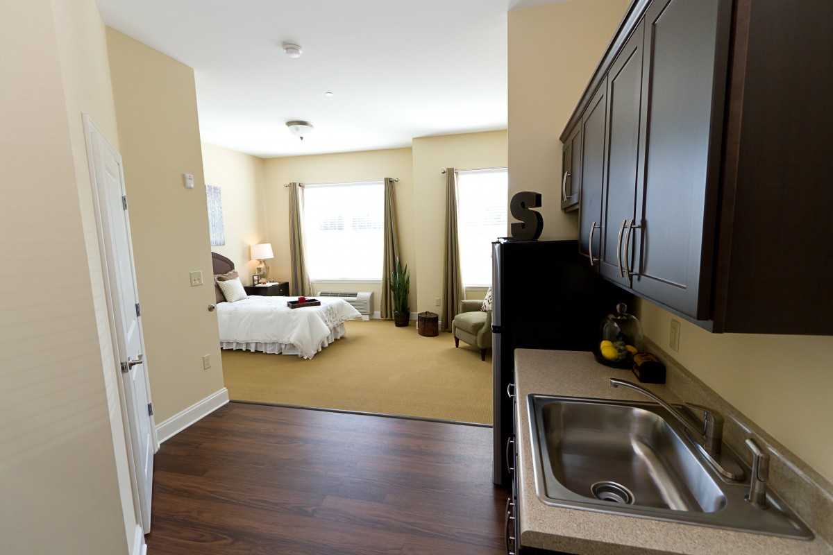 A cozy studio apartment with a kitchenette and a well-lit bedroom area.