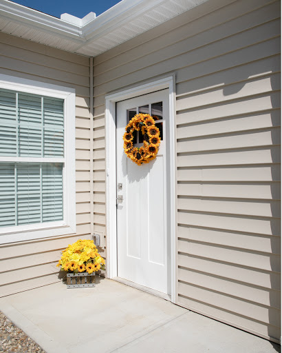 A charming entrance featuring a white door adorned with a sunflower wreath and a basket of sunflowers.