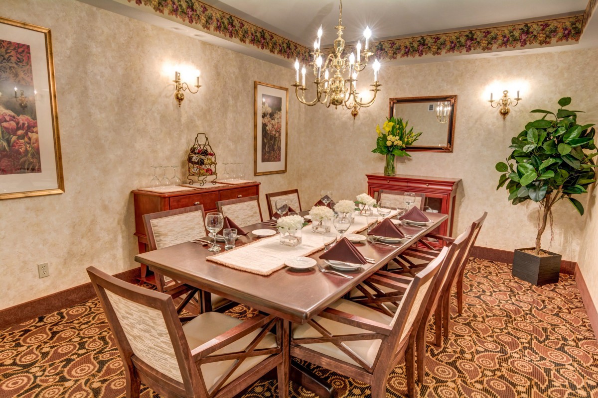 A formal dining room with an elegantly set table and a chandelier overhead.