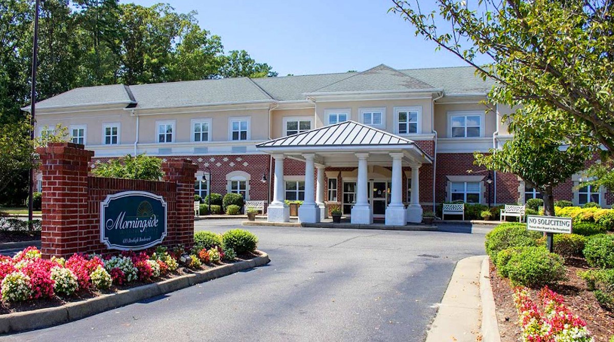 A modern building with a welcoming entrance, featuring white columns and landscaped surroundings.
