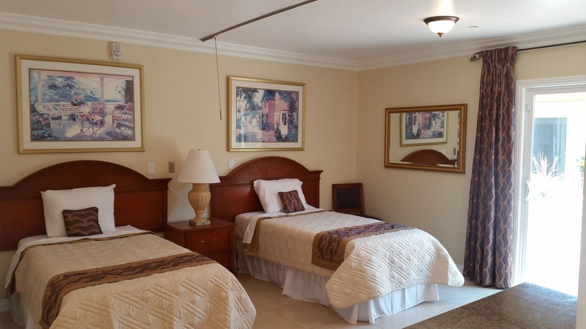 A cozy hotel room with two beds, warm lighting, and decorative artwork.