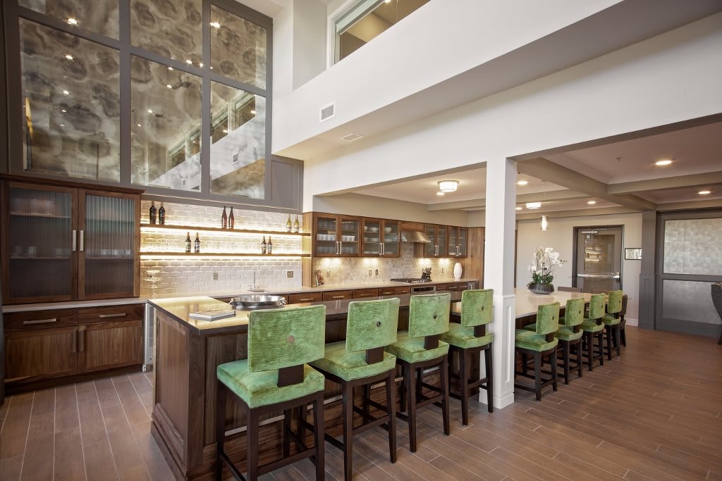 Modern kitchen with green bar stools and open design.