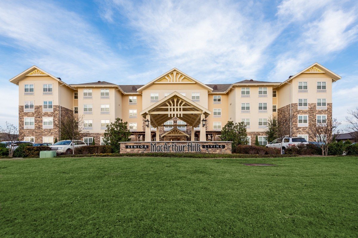 Front view of a hotel building with a landscaped lawn and clear sky.