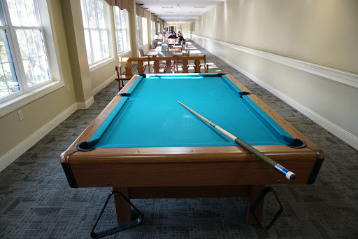 A well-lit game room featuring a blue felt pool table ready for a game.