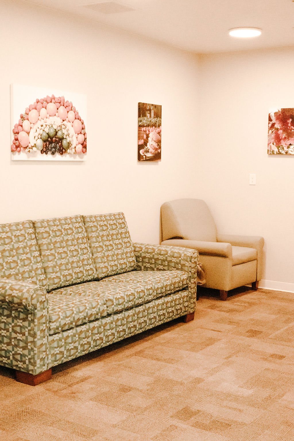 A cozy living room with a patterned sofa, an armchair, and decorative artwork on the walls.