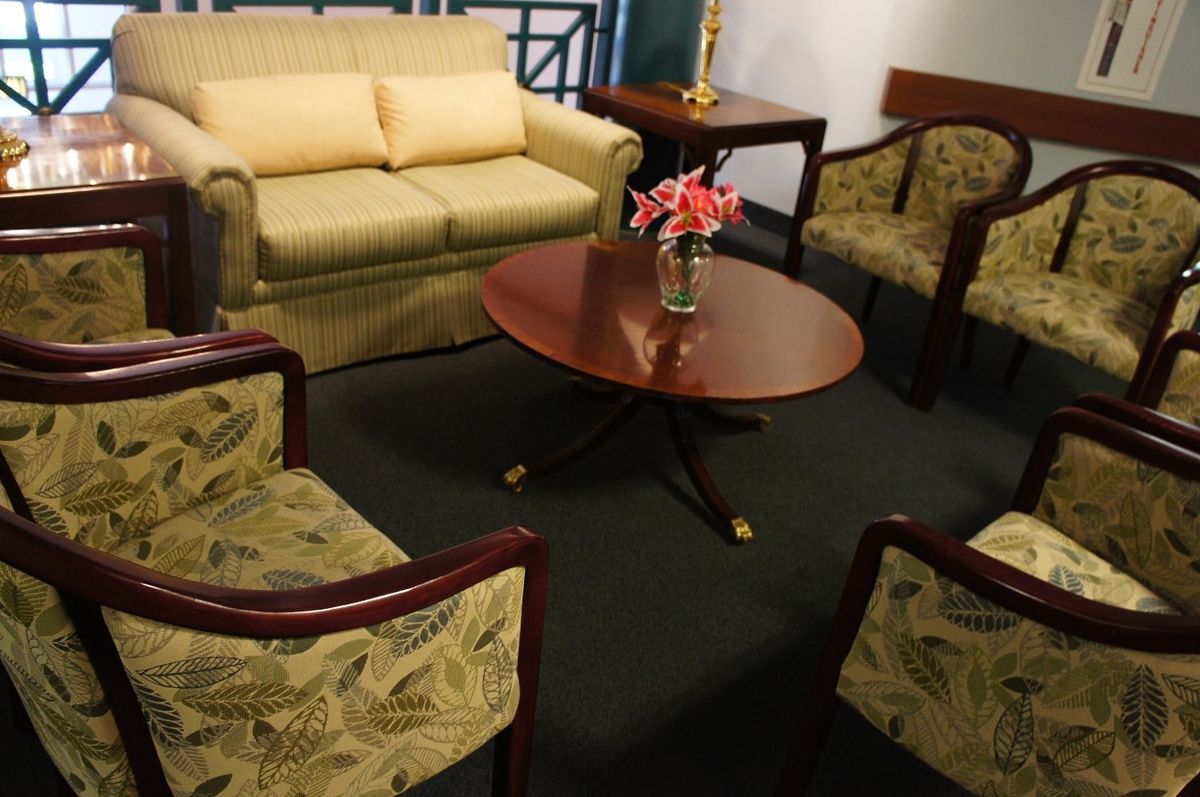 A cozy living room setup featuring a sofa, several chairs, and a round coffee table with flowers.