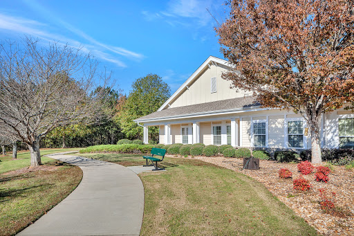 A serene view of a residential building surrounded by lush greenery and a winding pathway.