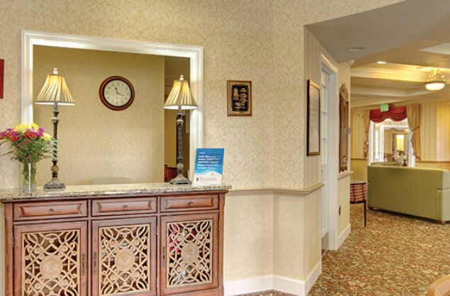 Reception area with a wooden desk, lamp, and visible hallway.