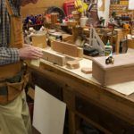 A craftsman working on a woodworking project in a well-equipped workshop.