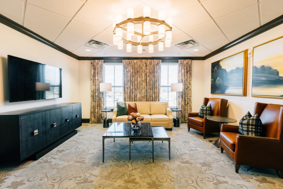 A stylishly decorated living room featuring a central chandelier, comfortable seating, and elegant decor.