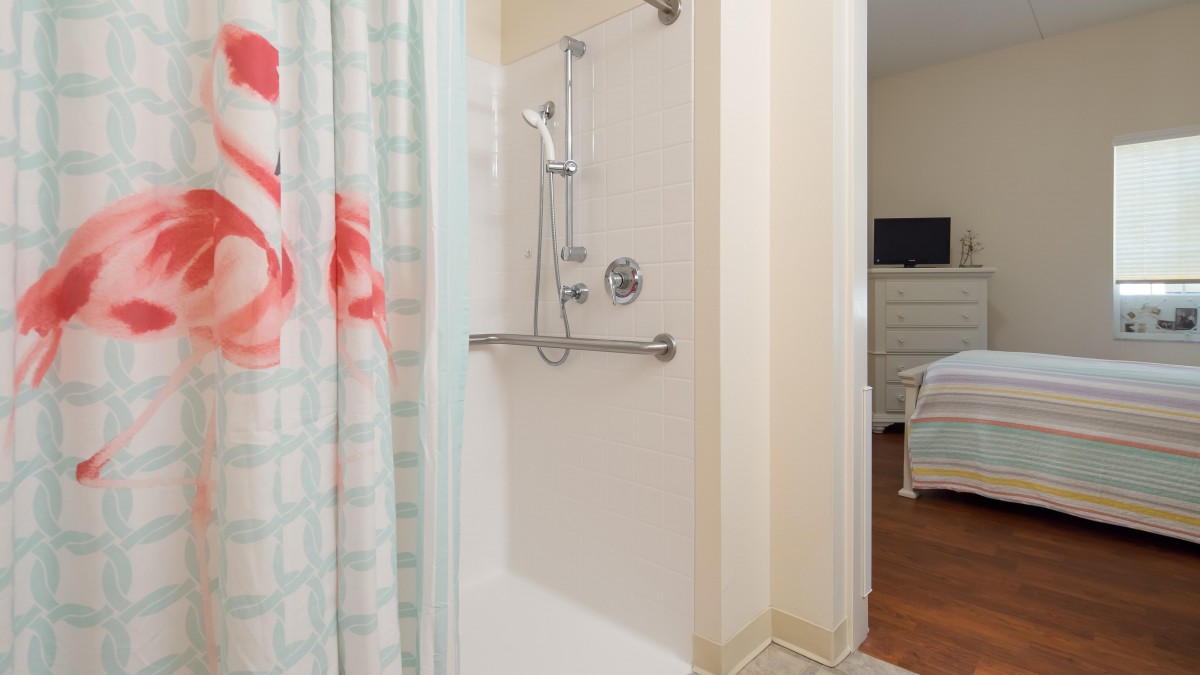 A modern bathroom featuring a shower with a curtain and a handrail.