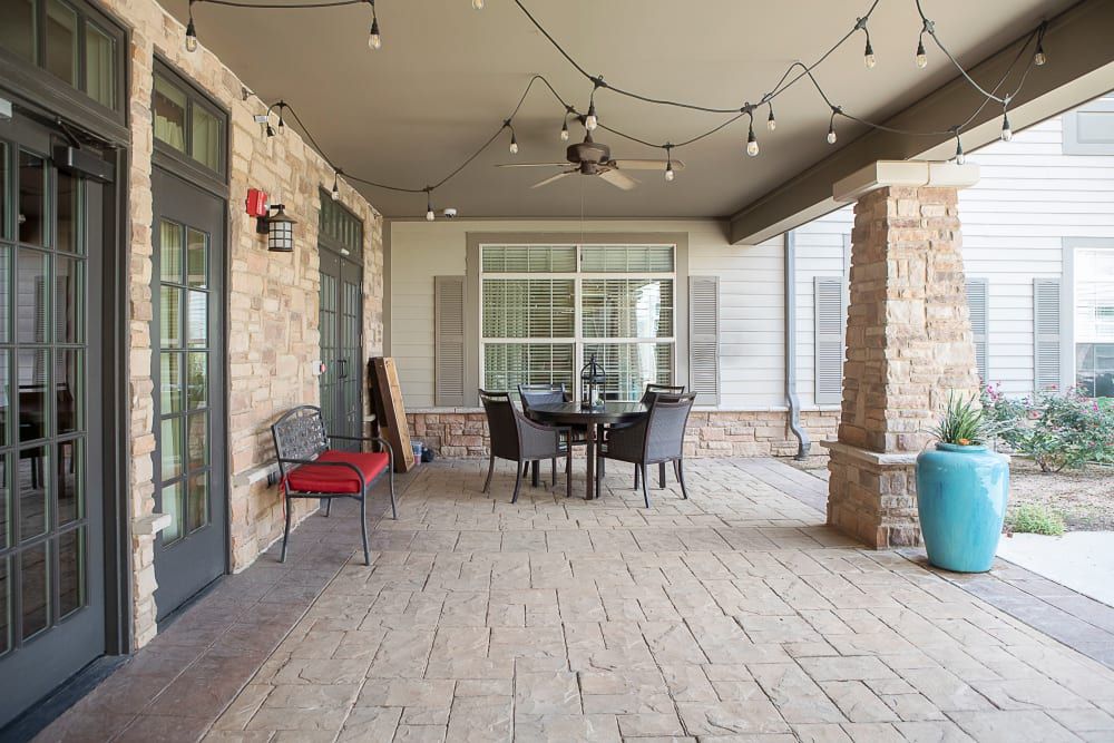 A cozy outdoor patio with seating and string lights on a covered porch.