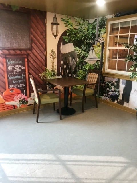 A cozy indoor cafe setting with a table and chairs surrounded by decorative plants and artwork on the walls.