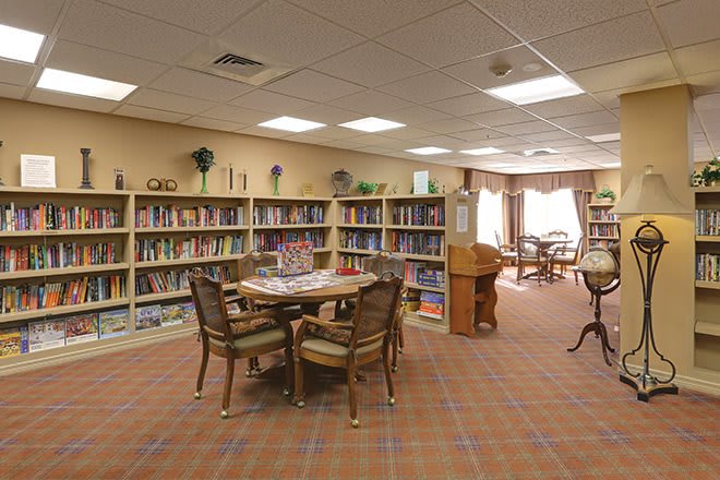 A cozy library room with bookshelves, a table, and chairs for reading.