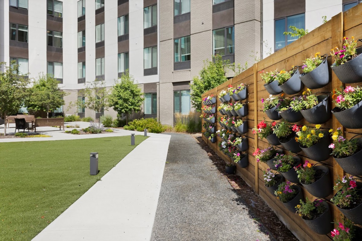 A modern apartment complex featuring a beautifully landscaped outdoor space with a vertical garden.