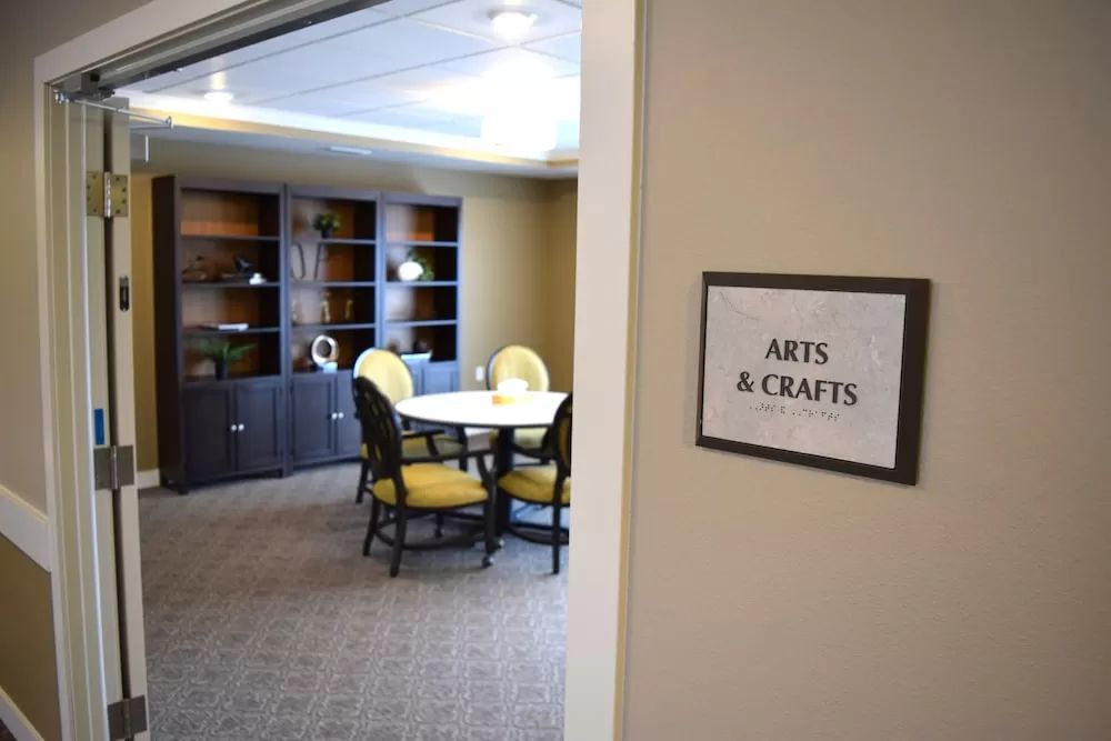 A neatly organized arts and crafts room with a table, chairs, and shelves.
