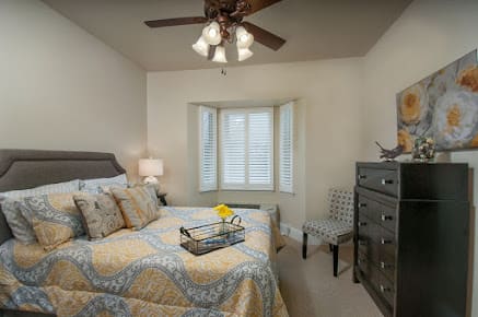 A cozy bedroom with a neatly made bed, dresser, and a chair by the window.