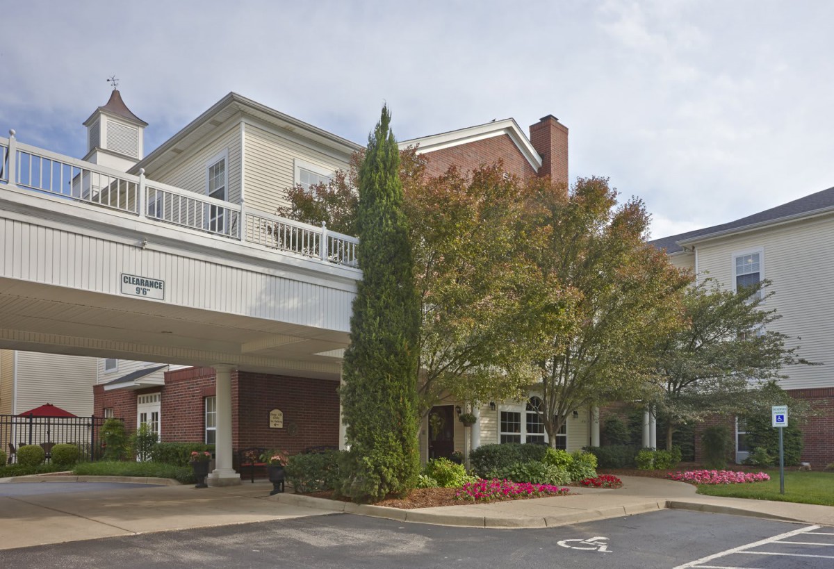 A well-maintained building entrance surrounded by greenery and trees.