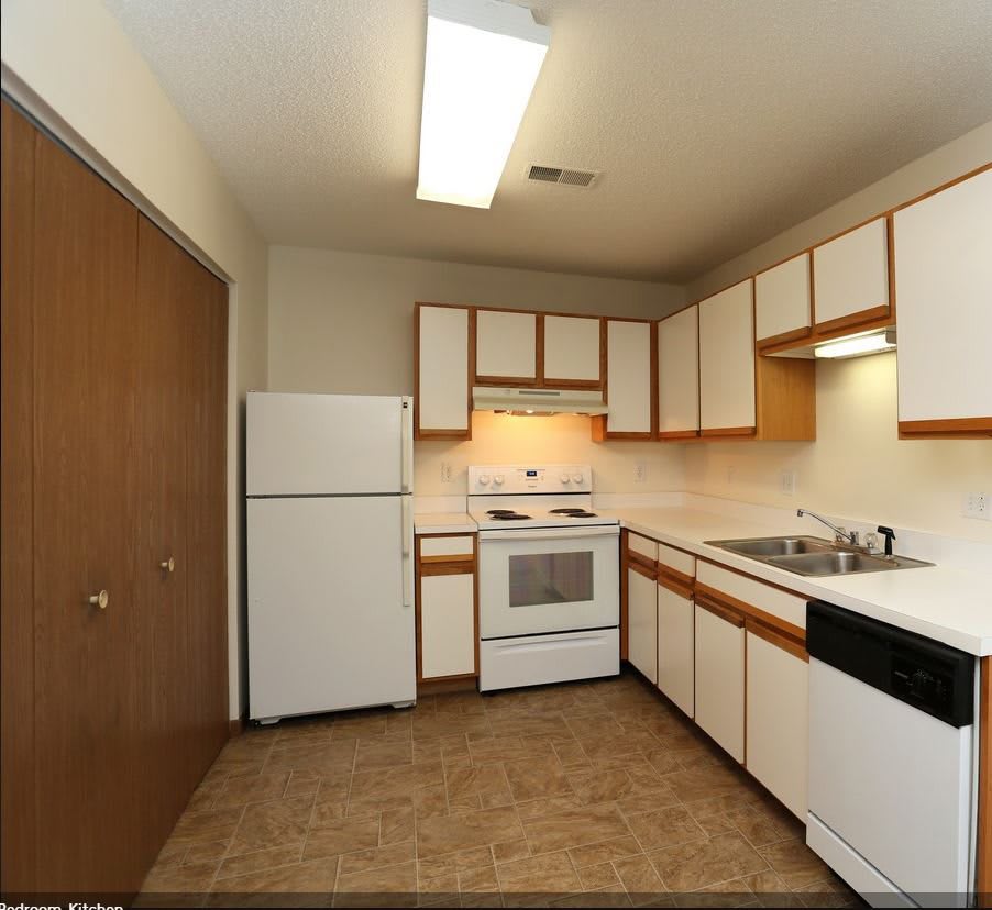A small kitchen with white appliances and wooden cabinets.