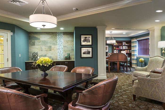 A stylish dining room with a dark wood table, leather chairs, elegant lighting, and decorative elements.