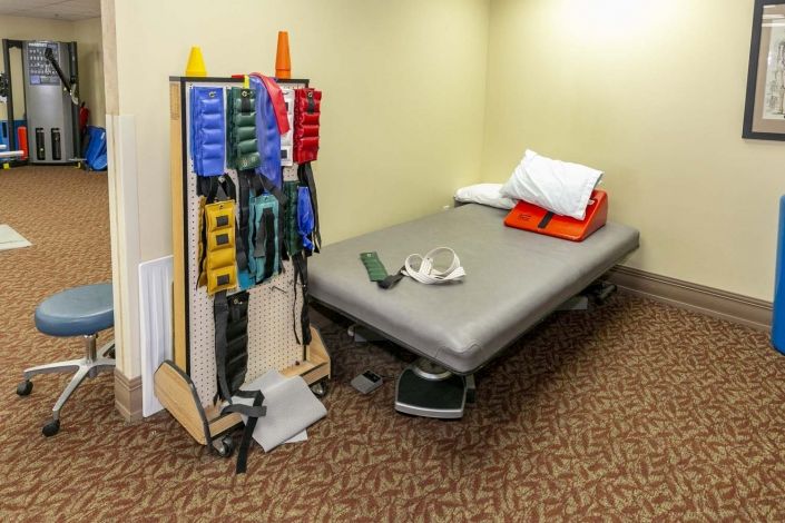 A physical therapy room with a treatment bed and various rehabilitation equipment.