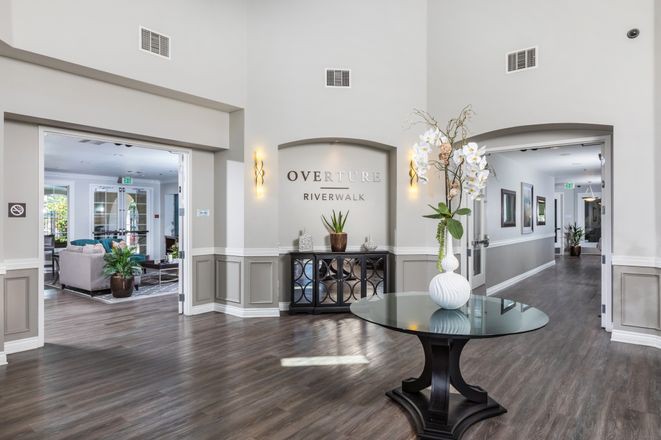 A modern lobby area featuring elegant decor, with a central table adorned with a vase and plants.