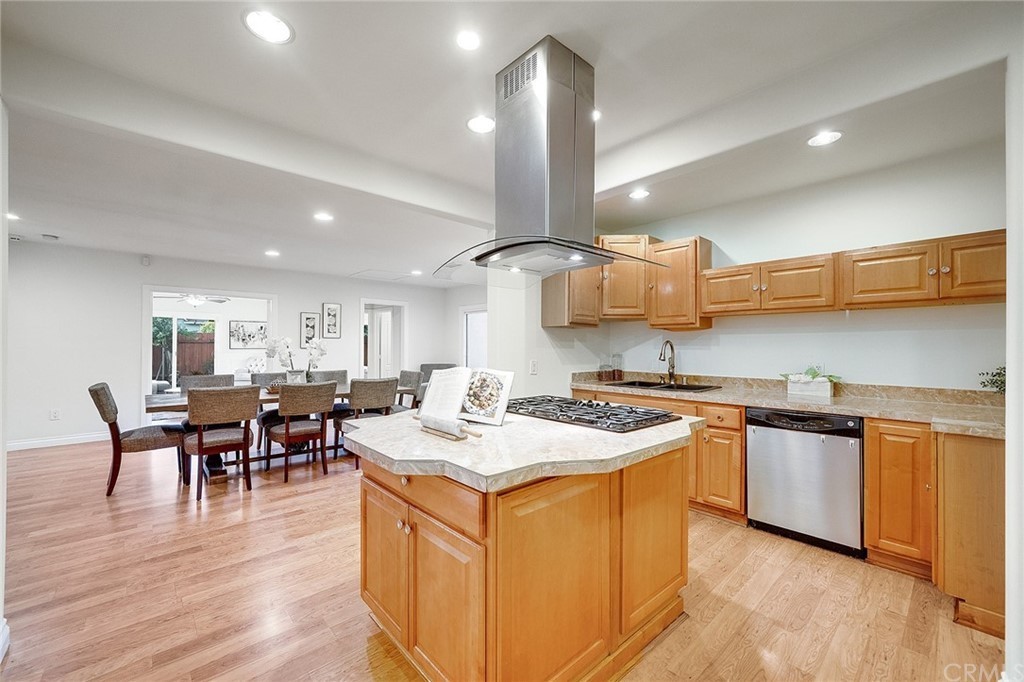 A modern kitchen with wooden cabinets, central island, and adjoining dining area.