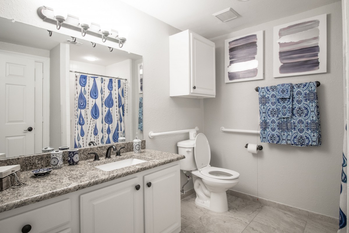 A modern bathroom with white cabinets and blue accents.