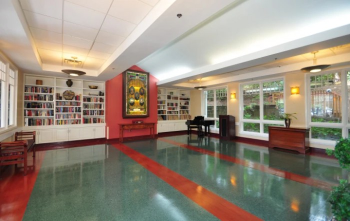 A spacious hallway with a piano, large artwork on the wall, and ample natural light from multiple windows.