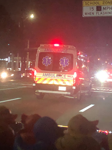 An ambulance with flashing emergency lights navigating through nighttime traffic.
