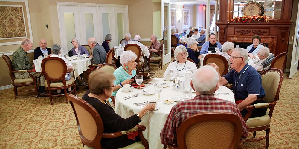 A group of seniors enjoying a meal together in a dining hall setting.