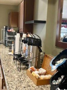 A self-service breakfast buffet with coffee, pastries, and drinks.
