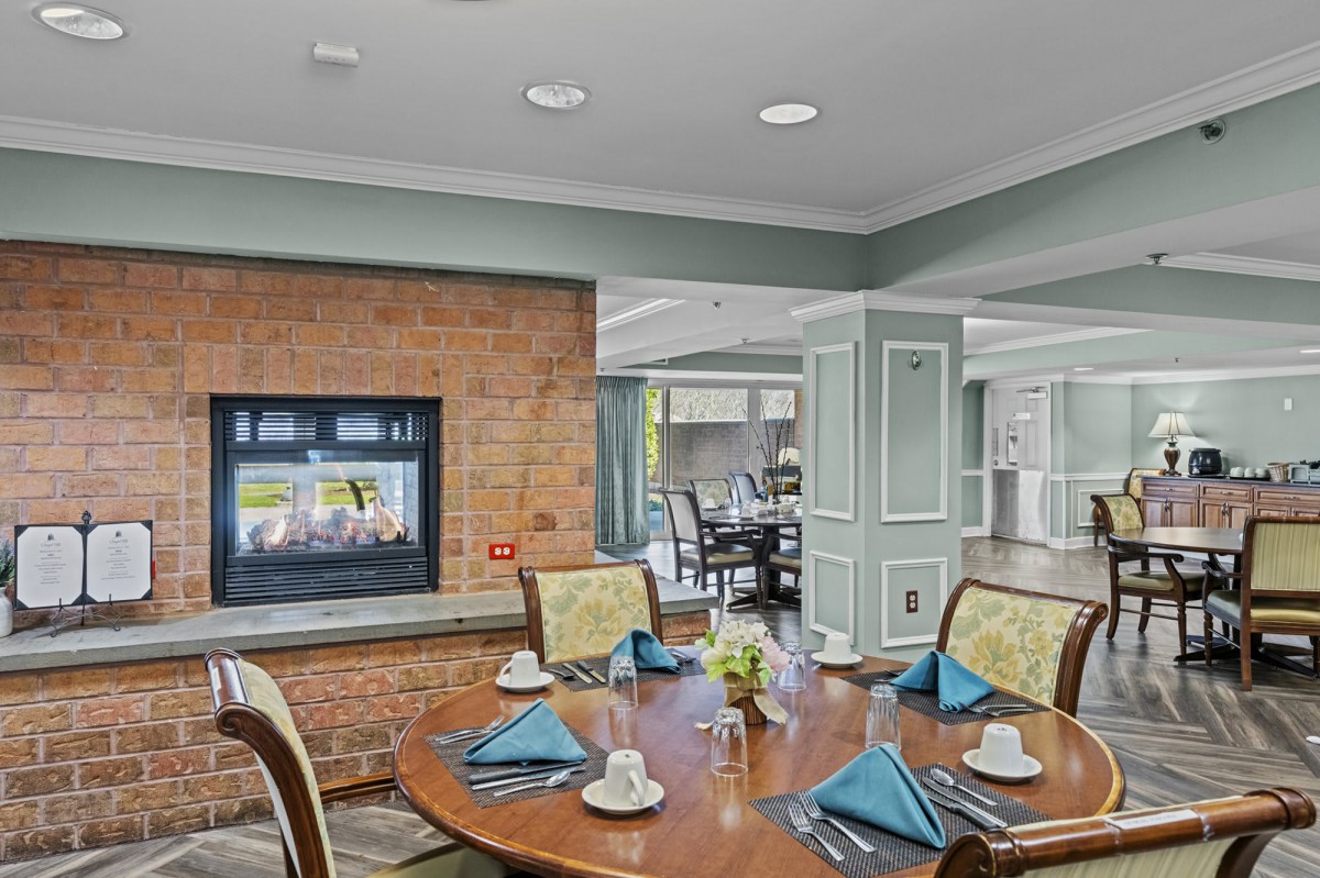 A neatly set dining table in a cozy interior with a fireplace.