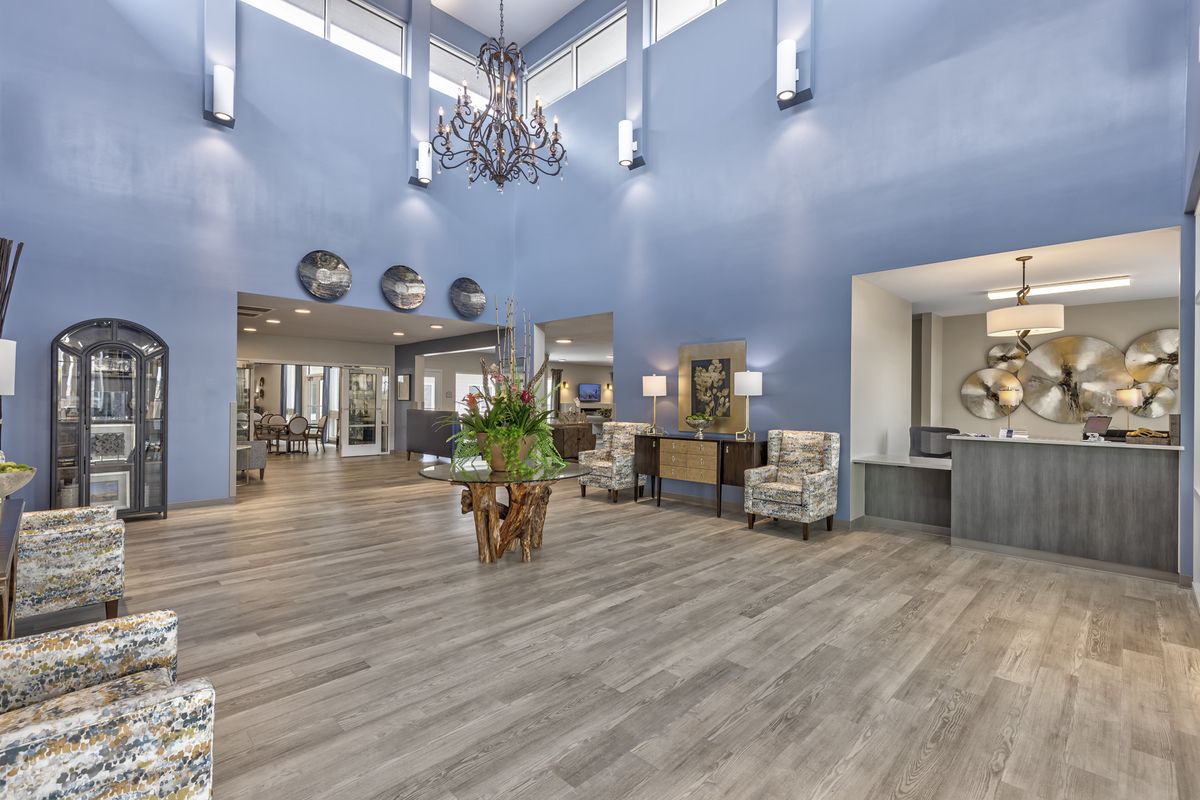 A spacious and modern lobby with a chandelier hanging from the ceiling, featuring elegant seating and a reception desk.