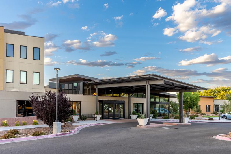 A modern hotel entrance with a covered driveway and clear blue sky.