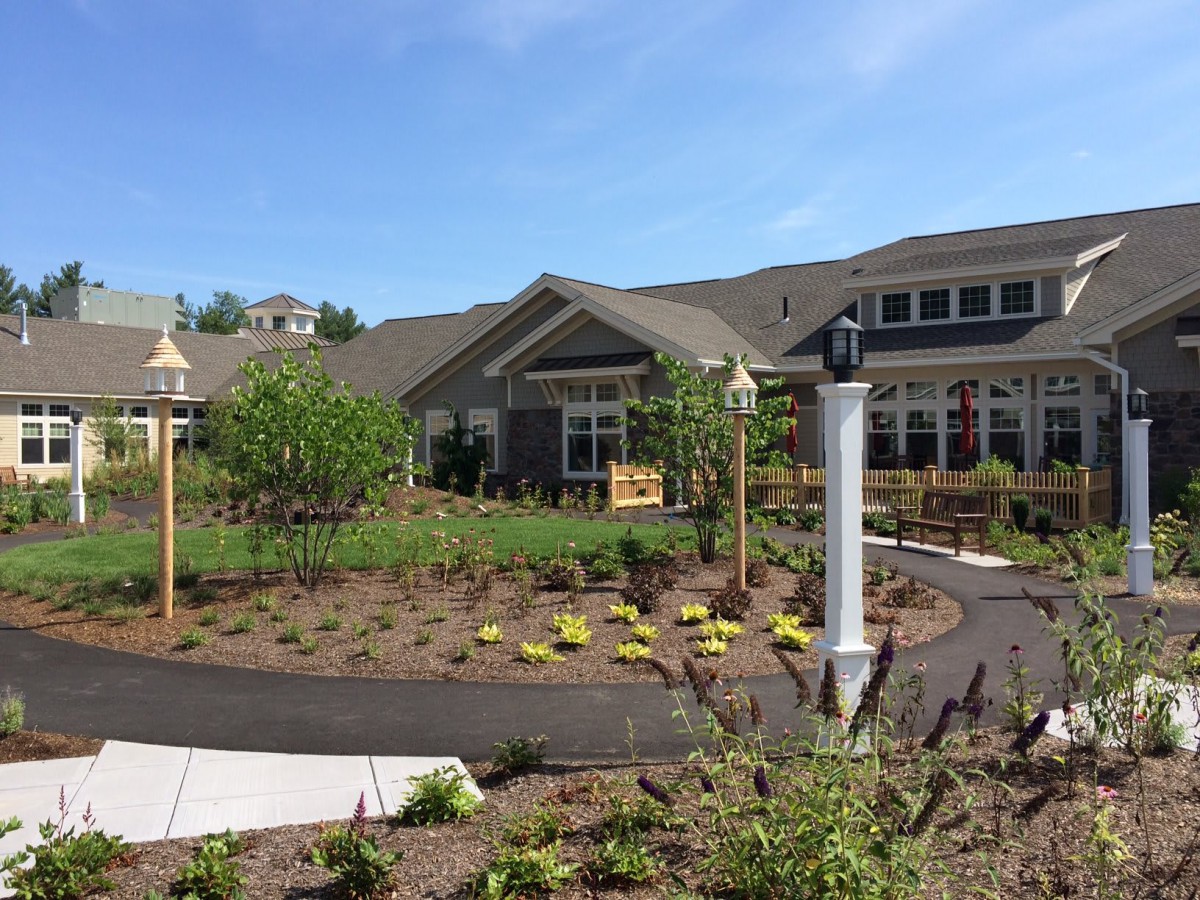 A well-maintained garden area in front of a residential building with clear blue skies.
