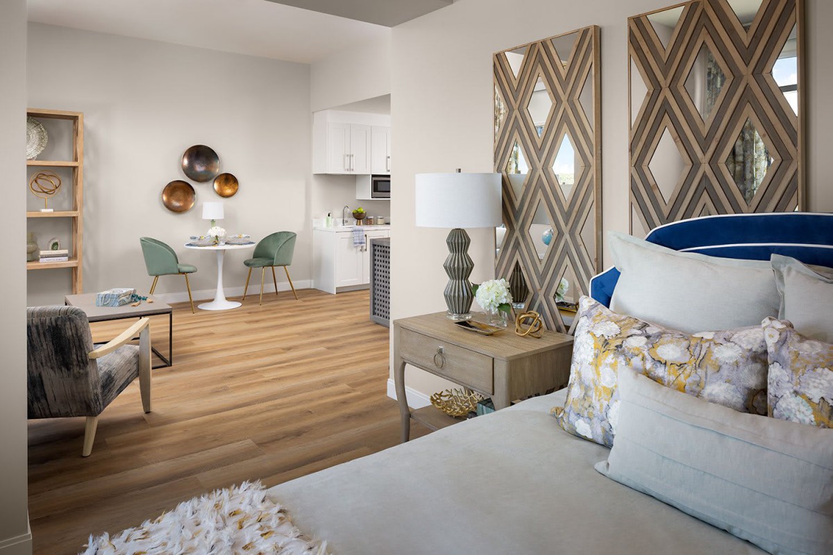 A modern living space featuring a cozy bedroom area with decorative wall art and a dining nook, illuminated by natural light.