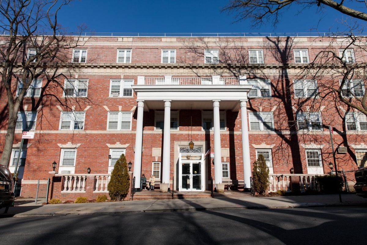 A historic brick building with white columns under a clear blue sky.