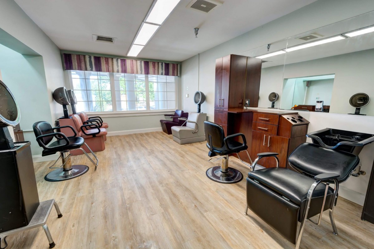 A spacious beauty salon with modern decor, featuring several styling stations and comfortable seating.