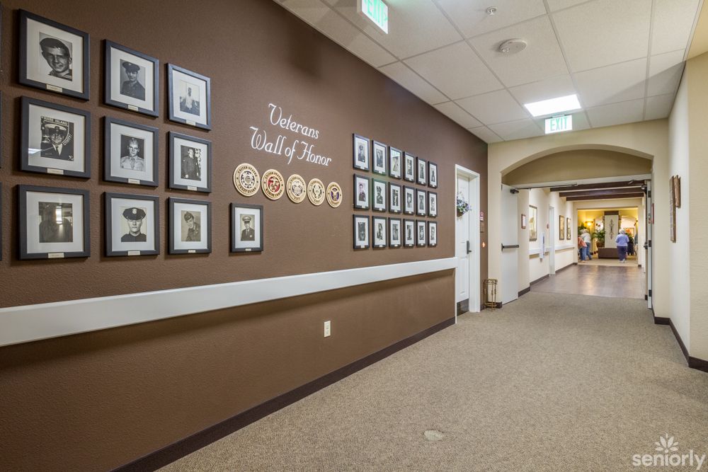 A hallway featuring a Wall of Honor with framed pictures and plaques on brown walls.