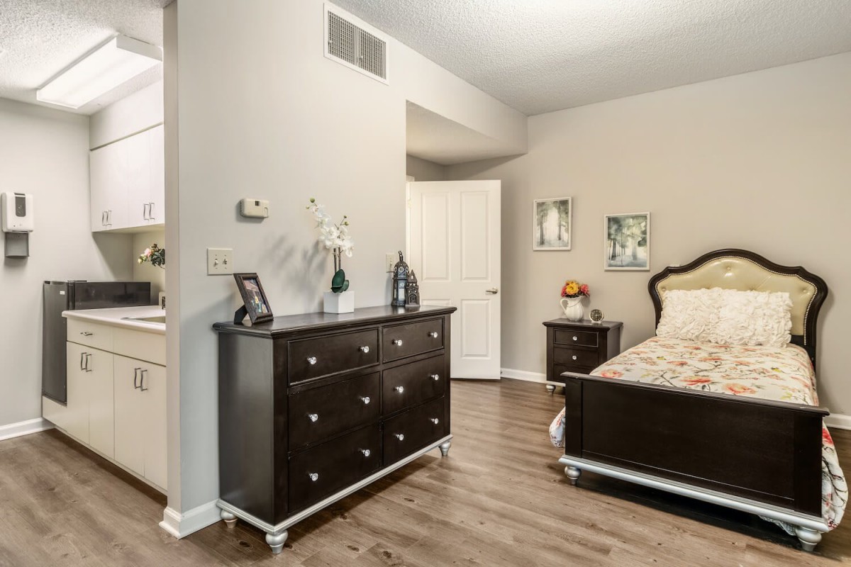 A well-furnished bedroom with a dark wooden dresser and matching bed, showcasing elegant interior design.