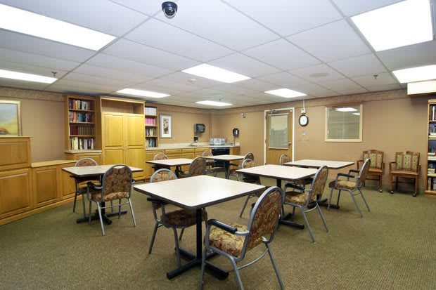 A classroom with tables, chairs, and bookshelves.