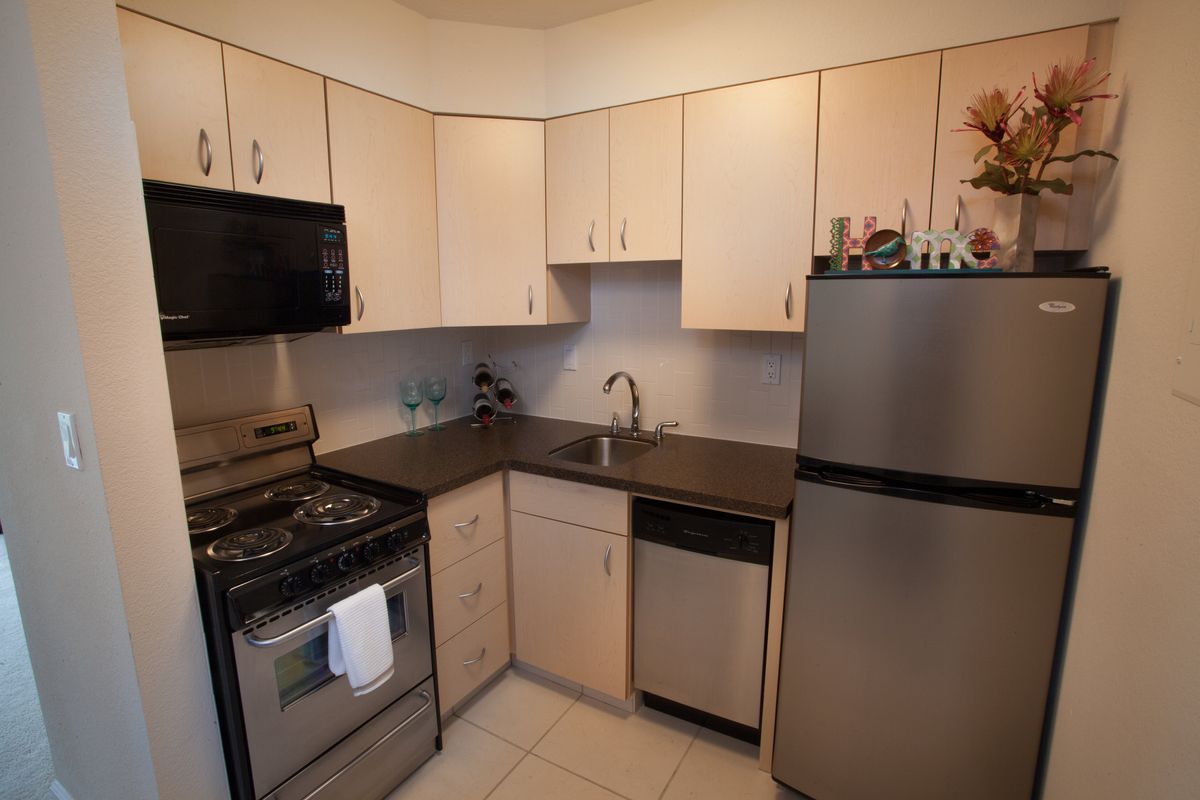 A compact kitchen with modern appliances, including a stove, refrigerator, microwave, and sink.