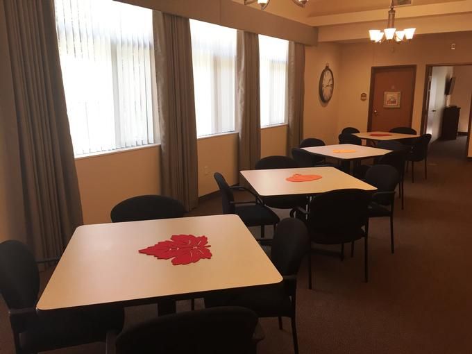 An empty meeting room with tables and chairs arranged in a well-lit space.