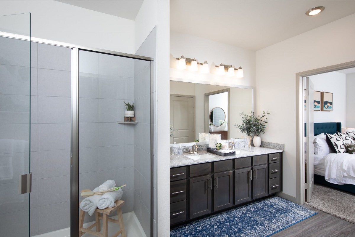 A modern bathroom with a large vanity and shower, complemented by stylish decor and plants.